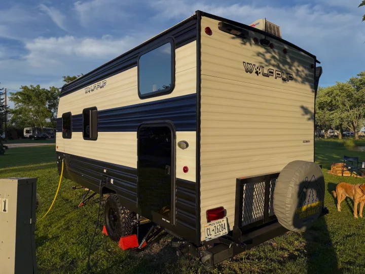 This Wolf Pup travel trailer, ideal for an RV rental, is parked at a sunny campsite, complete with a dog.. Forest River Cherokee Wolf Pup 2024