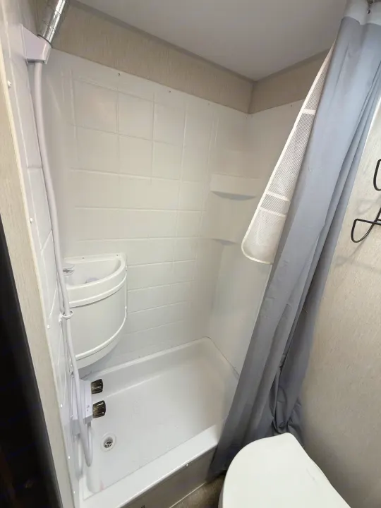 RV rental: Compact white shower stall with small sink, shower head, & toilet. Ideal for efficient use of space.. Forest River Cherokee Wolf Pup 2024