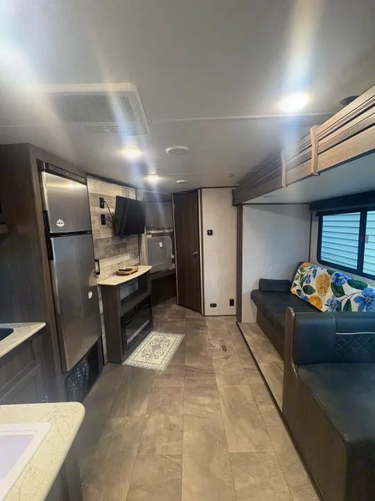 Modern RV rental interior with kitchen, living area, fireplace, and sofa. Bright, spacious travel trailer.. Dutchmen Kodiak SE 2021