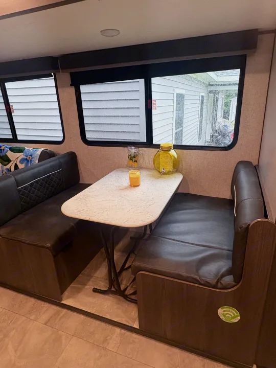 Cozy RV rental dinette with dark booth seating, a table, and windows. Perfect for meals on your road trip adventure.. Dutchmen Kodiak SE 2021