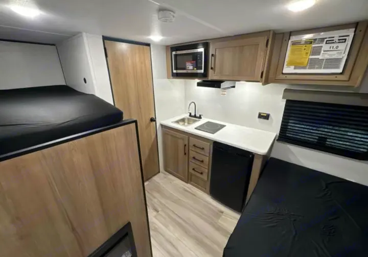 rv rental: Modern interior features bunk beds, a compact kitchenette with microwave & fridge, plus a cozy sleeping/seating area.. 4YDTCME14TM932345 13B 2025