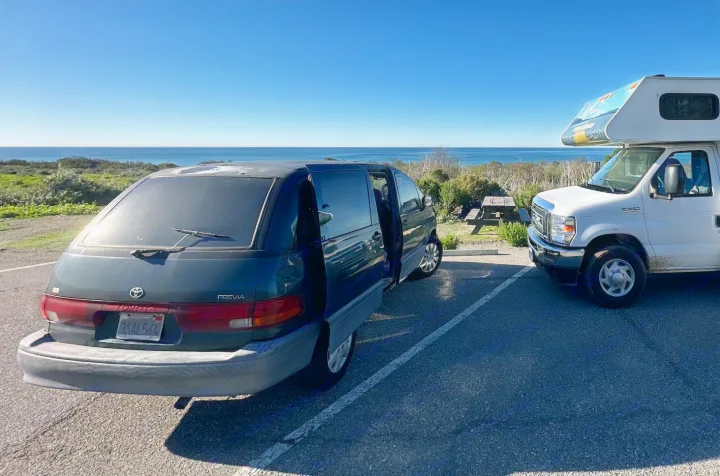 An RV rental and minivan are parked with an ocean view. Perfect for coastal adventures.. Toyota Previa 1996