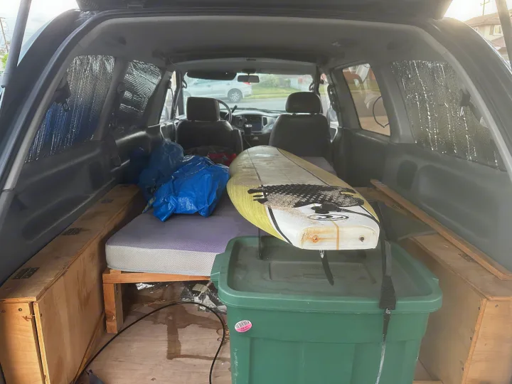 Inside a custom camper van: surfboard, built-in bed, and storage. Perfect for your rv rental camping adventure!. Toyota Previa 1996
