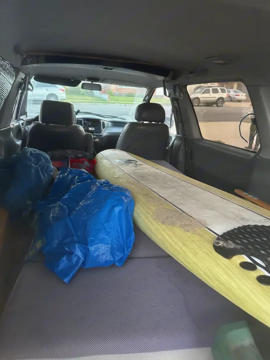 rv rental interior: surfboard, blue bags on a bed. View of road ahead. Perfect for surf travel or adventure.. Toyota Previa 1996