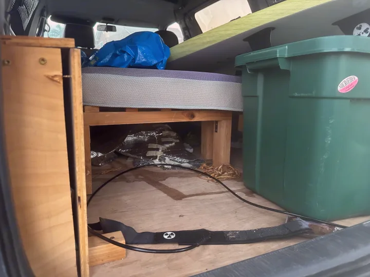RV rental interior: DIY bed, green storage, and surfboard, set up for a campervan adventure.. Toyota Previa 1996