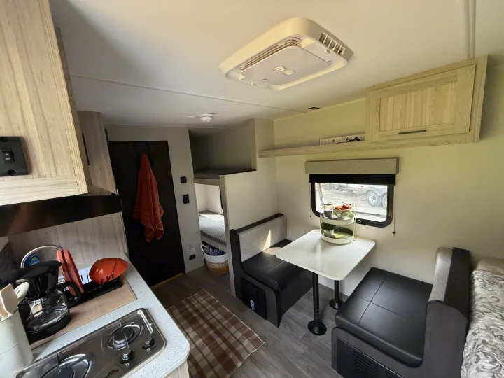 Step inside this RV rental! Features a compact kitchen, comfortable dining booth, and bunk beds, ideal for family travel.. Heartland's RV Mallard 17 BHL 2025
