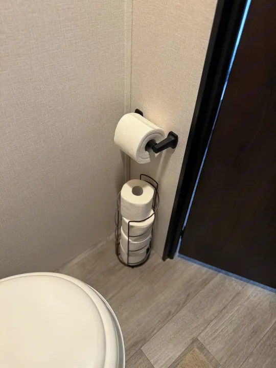 RV rental: White toilet, toilet paper on black wall-mounted holder, & reserve rolls in a floor stand.. Heartland's RV Mallard 17 BHL 2025