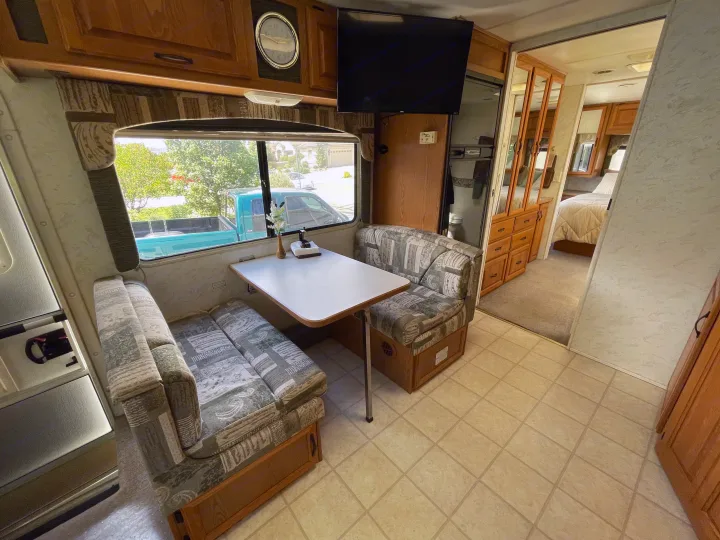 RV rental interior features a dinette, window view, TV, overhead storage, and passage to the bedroom.. Four Winds Hurricane 2000