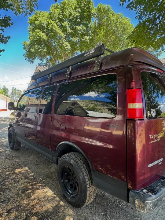AWD Chevy Express camper van RV rental, burgundy with an awning & off-road tires, ready for adventure.. Chevrolet Open Road 2005
