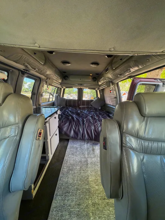 Step inside this RV rental featuring a comfortable bed, compact kitchen, and spacious captain's chairs.. Chevrolet Open Road 2005