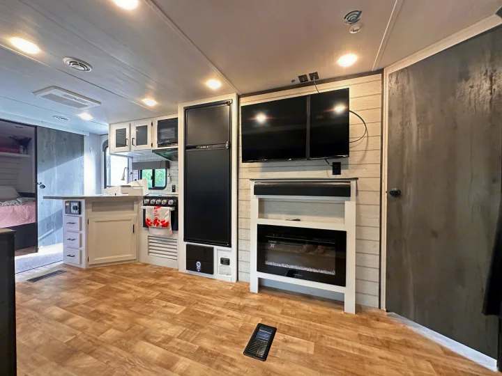 Spacious rv rental interior showcasing a bright kitchen, TV, soundbar, and electric fireplace for comfortable travel.. Keystone RV Hideout 2023