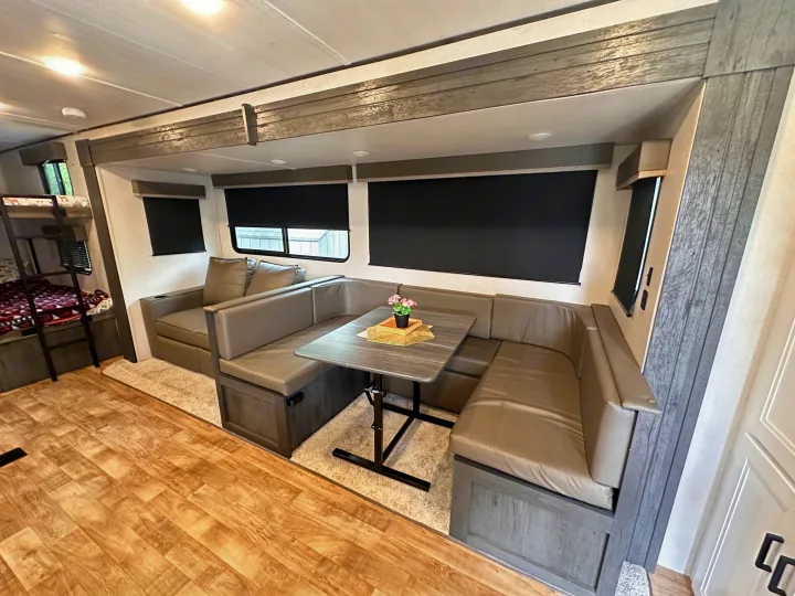 RV rental interior featuring a spacious dinette, blackout blinds, and bunk beds, offering comfortable living space.. Keystone RV Hideout 2023