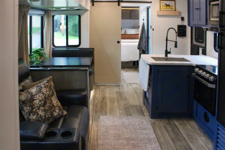 Stylish RV rental: blue kitchen, dining, comfy couch, and barn door leading to the bedroom. Ideal for your next adventure.. Keystone RV Outback Ultra-Lite 2021