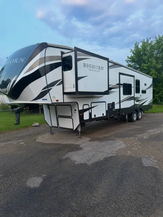 White and black Bighorn Traveler fifth-wheel RV rental, with slides extended, parked on an asphalt lot.. Heartland RVs Bighorn Traveler 2022