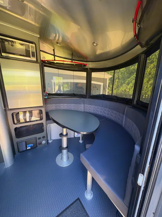 Explore this modern RV rental! Features a comfortable U-shaped dinette, panoramic views, and a compact kitchen area with microwave.. Airstream Basecamp 2025