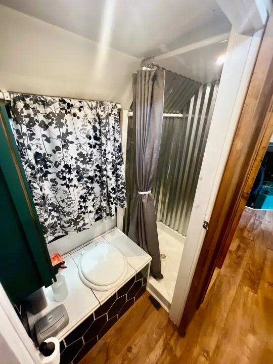 This compact RV rental bathroom features a toilet on a tiled base, a shower with corrugated metal walls, and two curtains.. Chevy C4500 Kodiak 2008