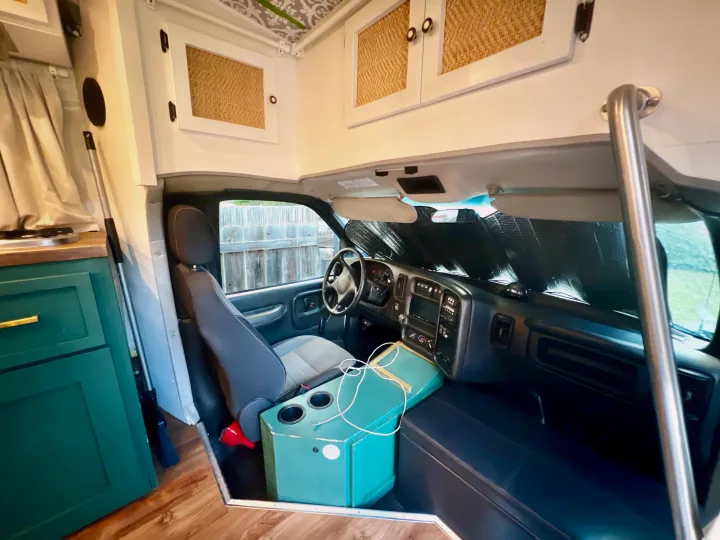 Rv rental interior: view into the driver's cockpit with sunshade, green console, and woven overhead cabinets.. Chevy C4500 Kodiak 2008