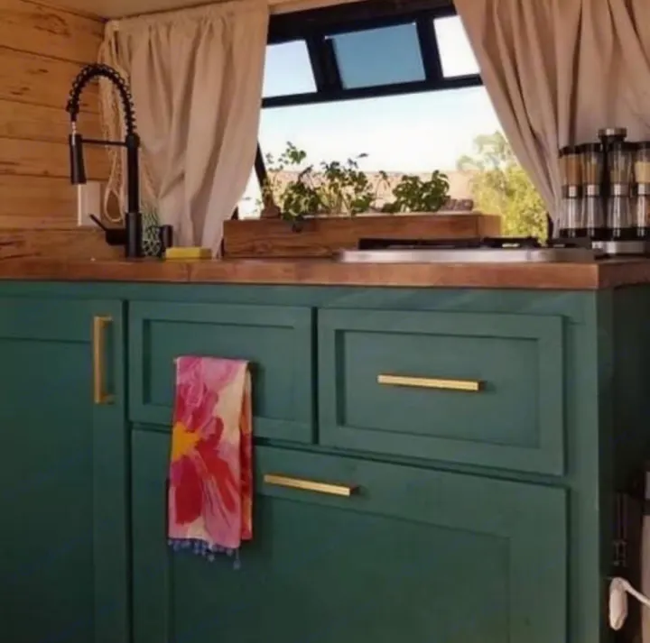 Cozy RV rental kitchen featuring deep green cabinets, wood counters, black faucet, and a window herb garden.. Chevy C4500 Kodiak 2008