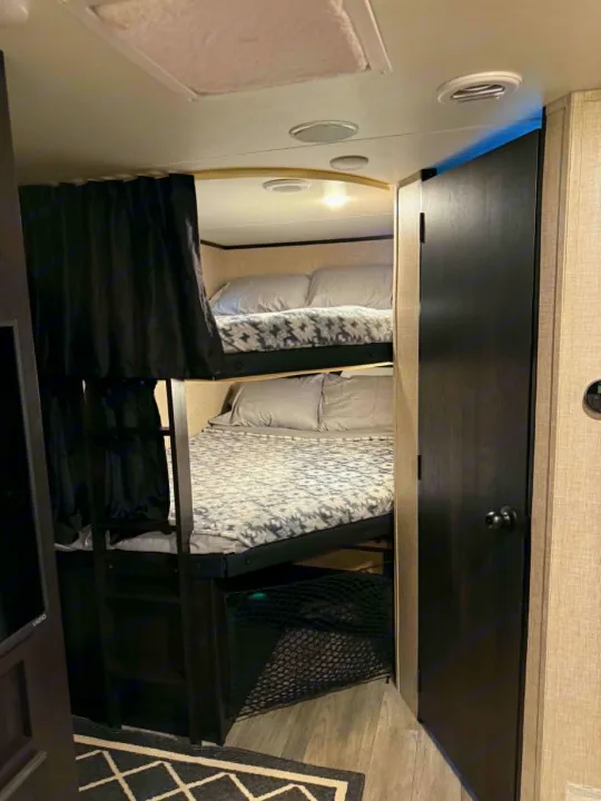 Cozy RV rental bunk beds with privacy curtains, ladder, and comfortable bedding. Perfect for families on the road.. Jayco Jay Feather 2023