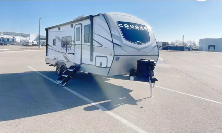 Exterior of a sleek Cougar travel trailer, ideal for an RV rental. This modern RV is parked on asphalt, ready for camping trips.. Keystone RV Cougar 2023