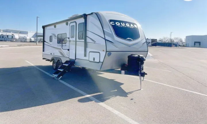 Ready for adventure: a modern Cougar Half-Ton travel trailer, ideal for your next rv rental, parked on asphalt.. Keystone RV Cougar 2023