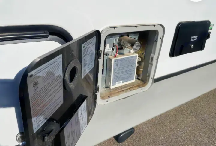 RV rental: Open RV water heater access panel and adjacent docking station on a camper's exterior side.. Keystone RV Cougar 2023