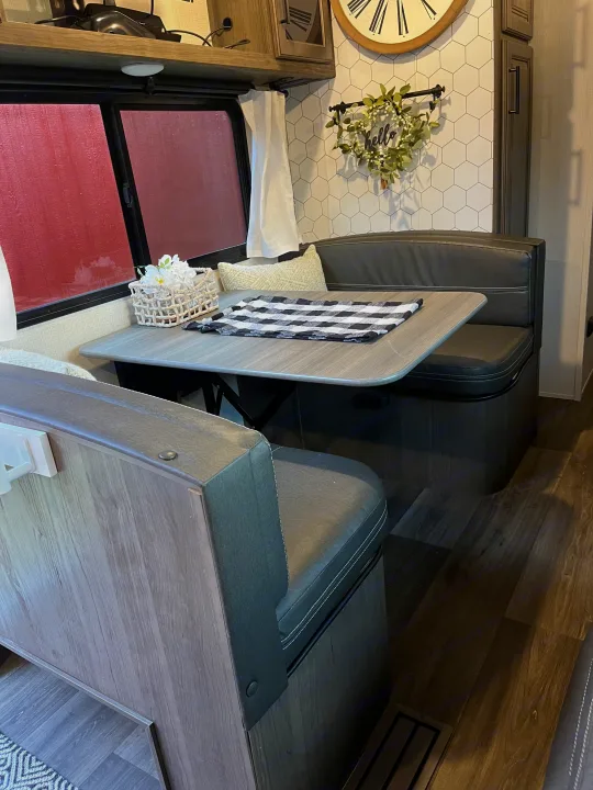 Stylish camper dinette in an RV rental, featuring dark seats, a light table, and a hexagonal wall design.. Keystone RV Cougar 2023