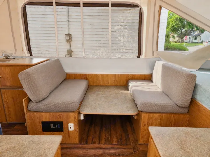 RV rental: Inside a pop-up camper dinette with grey cushioned benches, a table, wooden cabinetry, and a sink area.. Viking 1906 2001