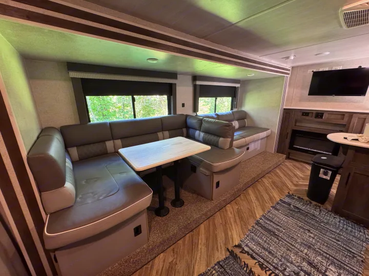 Spacious RV rental interior featuring a comfortable dinette with table, scenic window views, TV, and an electric fireplace.. Forest River Salem Cruise Lite 2022