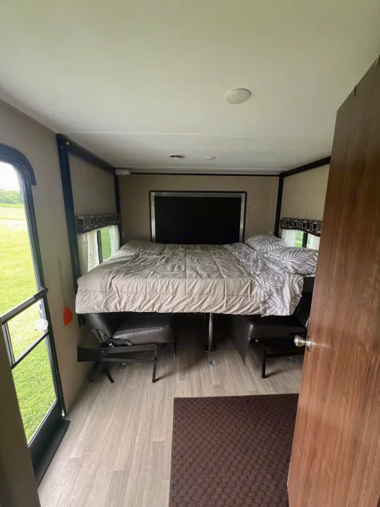RV rental interior featuring a lowered bed over convertible seating/dining, with outdoor views and wood flooring.. Coleman Lantern Series 2016