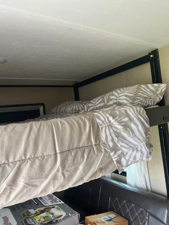 Cozy bunk bed in an RV rental with tropical leaf bedding, metal frame, and a quilted leather couch below.. Coleman Lantern Series 2016