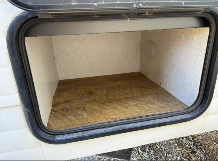 Clean, empty exterior storage compartment of an RV rental, with wood-look floor, ready for your adventure.. Sunset Park RV SunRay 2024
