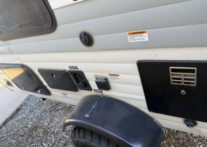 RV rental utility panel: fresh/city water connections, electrical inlet, and access hatches on the exterior.. Sunset Park RV SunRay 2024