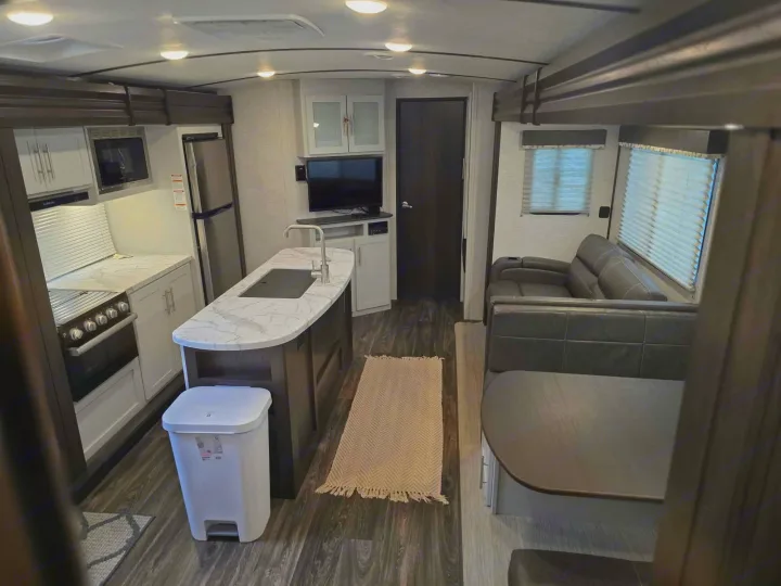 Spacious rv rental interior featuring a modern kitchen with island, living area with sofa, and dinette seating.. Keystone RV Bullet Ultra Lite 2021