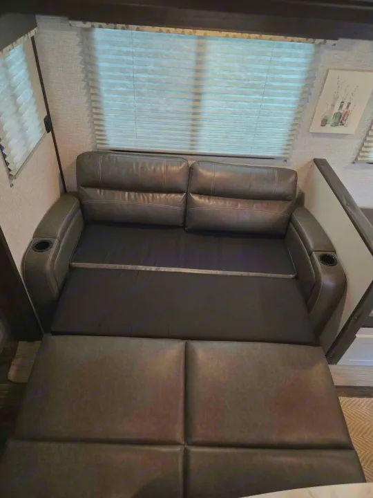 Comfortable pull-out sofa in an RV rental, converting to a sleeping area for added space and convenience.. Keystone RV Bullet Ultra Lite 2021