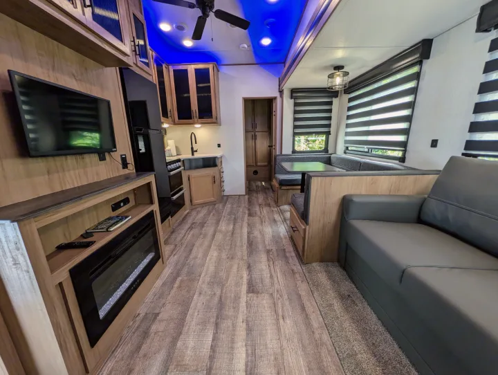 Experience comfort in this modern RV rental: open living, kitchen, and dining space with fireplace & blue ceiling lights.. Cherokee limited Arctic Wolf 2023