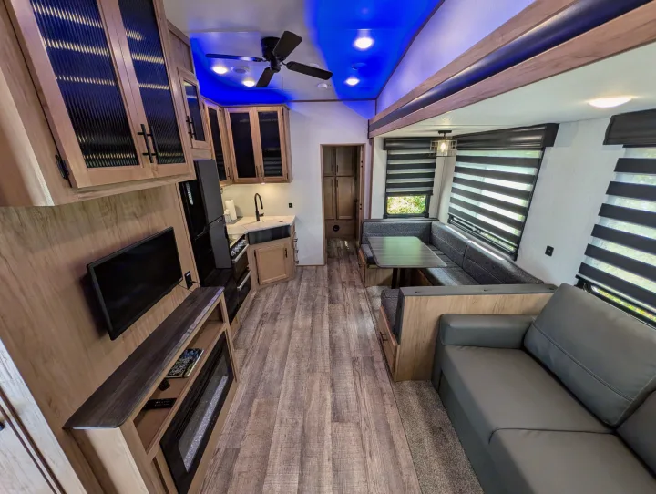 Spacious rv rental interior showing kitchen, living room, and dining nook with blue accent lighting. Perfect for travel comfort.. Cherokee limited Arctic Wolf 2023