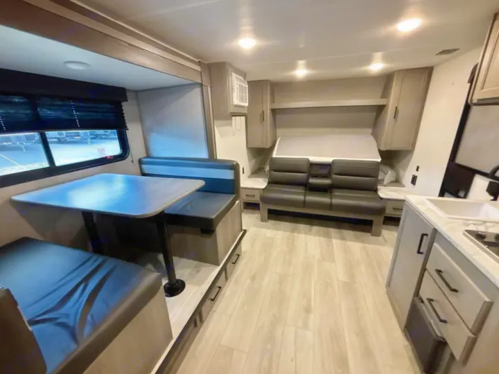 This RV rental interior offers a dinette, a versatile sleeping area, and a compact kitchen for your travels.. Keystone RV Hideout Sport 2025