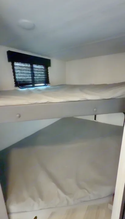 RV rental bunk beds: Two sleeping levels with mattresses and a window, offering compact sleeping space for your adventure.. Keystone RV Hideout Sport 2025