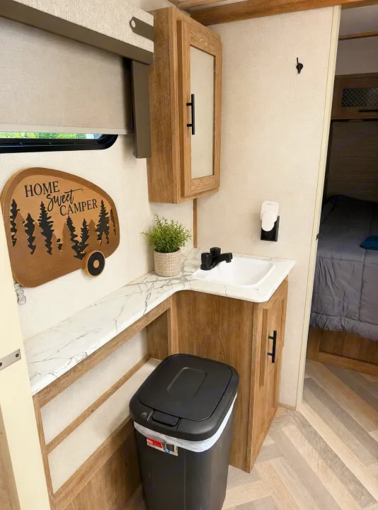 RV rental bathroom vanity area featuring a sink, mirrored cabinet, and 'Home Sweet Camper' decor. Compact and functional.. Forest River Salem 2021