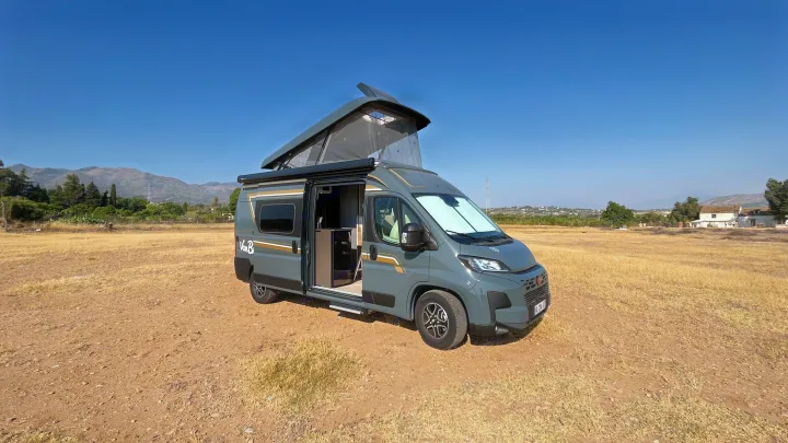 Explore nature with this rv rental! A grey camper van, pop-top open, sits in a dry field under a clear blue sky, mountains afar.. BURSTNER B66 2024
