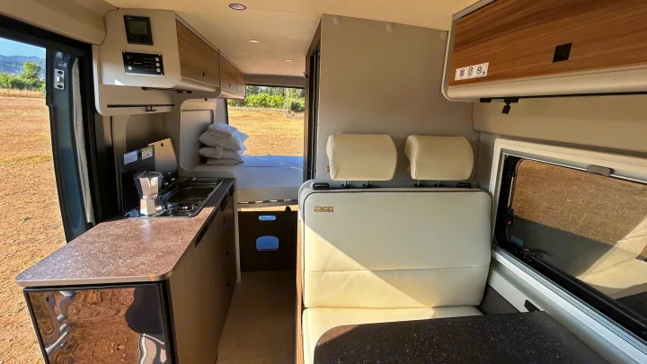Modern RV rental interior showing a compact kitchen, dining area, and rear bed, ready for comfortable road trip adventures.. BURSTNER B66 2024
