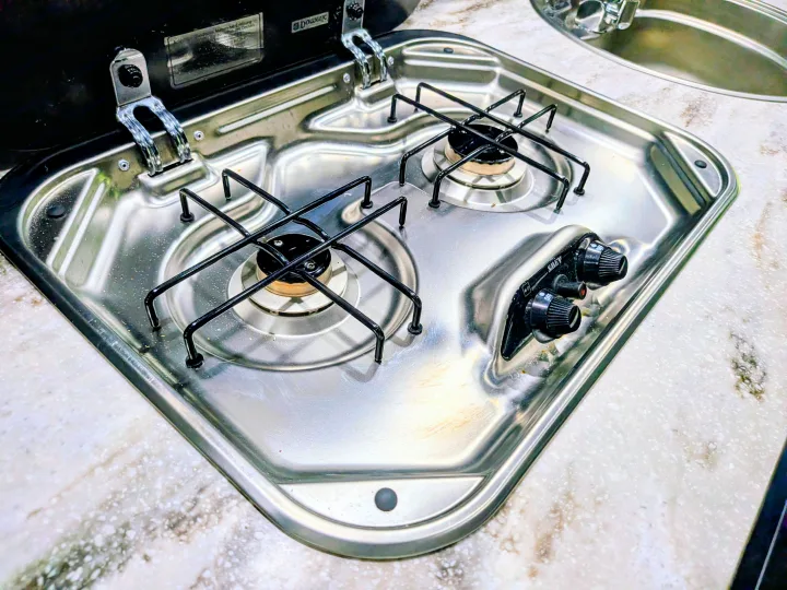 Compact stainless steel 2-burner gas cooktop with control knobs and grates in an RV rental kitchen, ready for cooking adventures.. Airstream Interstate 2017