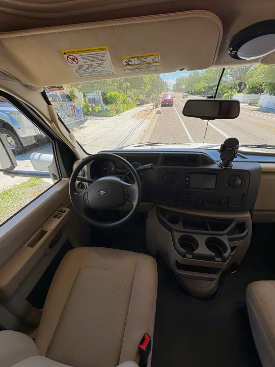 Driver's perspective inside an RV rental, featuring a Ford steering wheel, dashboard, and the road visible through the windshield.. Coachmen Freelander 2018