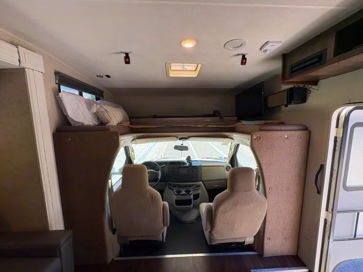 Spacious rv rental interior with overhead bed, cockpit, and living area, perfect for travel adventures.. Coachmen Freelander 2018