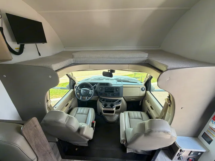 **RV rental**: Interior view of the motorhome's cab area, featuring seats, dashboard, and an overhead bunk bed.. Jayco Redhawk SE 31FF 2026
