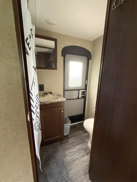 This rv rental bathroom includes a sink, vanity, toilet, and shower curtain, showcasing its practical, compact design.. Keystone RV Hideout Luxury 2017