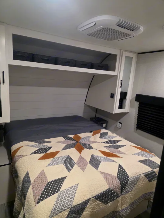 Comfortable RV rental bedroom featuring a patterned quilt, overhead storage, and AC for a relaxing trip.. JAYCO JAY FLIGHT SLX 2026