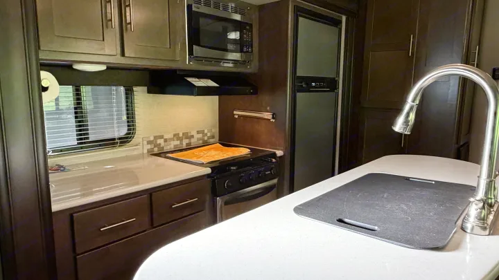 Modern RV rental kitchen showcasing appliances like a microwave, stovetop, fridge, sink, and ample counter space.. Crossroads RV Sunset Trail Grand Reserve 2017