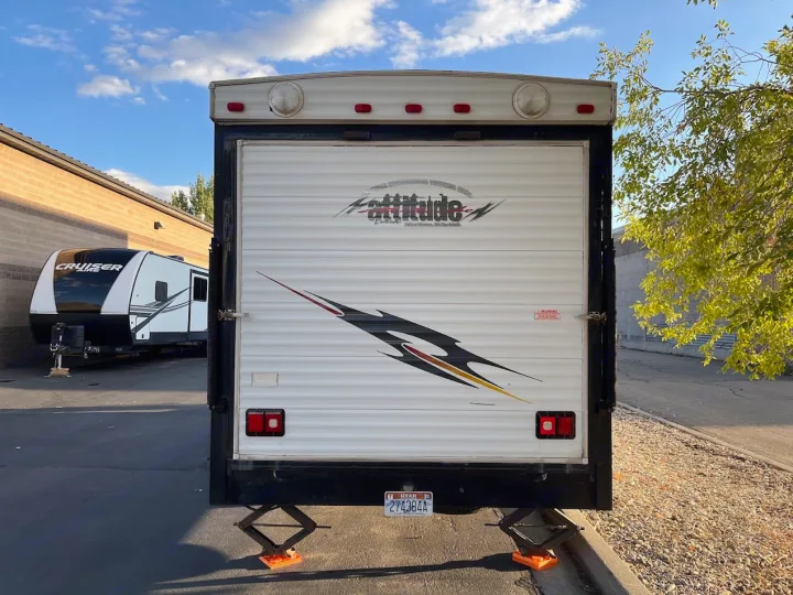 Rear view of an "Attitude" toy hauler RV rental, stabilized, parked next to a "Cruiser" travel trailer under a blue sky.. Eclipse Recreational Vehicles Attitude 2007